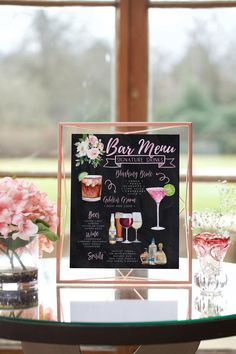 a menu is displayed on a table with pink flowers in vases and wine glasses