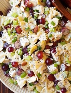 a pasta salad with grapes and nuts in a white bowl