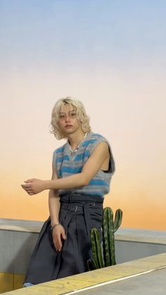 a woman standing on top of a roof next to a cactus in front of a painting