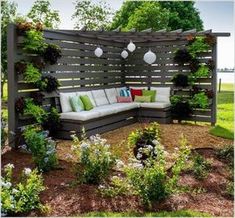 a couch sitting on top of a lush green field next to a wooden fence and trees