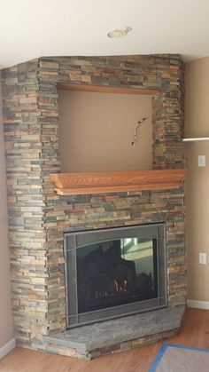 a stone fireplace with a wood mantle and shelves above it