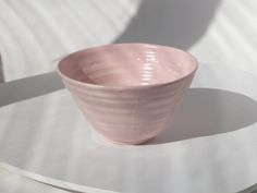 a pink bowl sitting on top of a white table