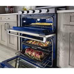 two open ovens in a kitchen with food cooking on the racks and under them