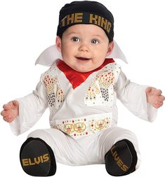 a baby dressed in elvis costume sitting on the ground with his hands out and smiling