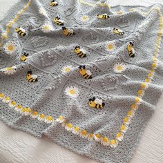 a crocheted blanket with yellow and white bees on it, sitting on a bed