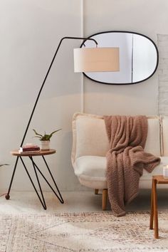 a living room with a white couch, mirror and black metal floor lamp on the wall