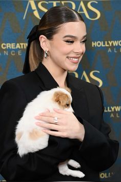 a woman holding a small white and brown dog in her arms at an awards event