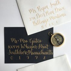 two envelopes with writing on them and a compass charm hanging from the top one