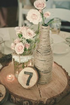 the table is set with flowers in vases, candles and napkins on wood slices