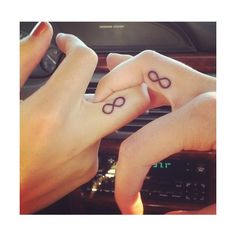 two people holding hands with tattoos on their fingers and the other hand is pointing at them