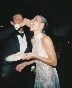 a man in a tuxedo feeding a woman a piece of food from a plate