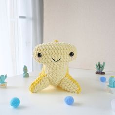 a crocheted stuffed animal sitting on top of a table next to cacti