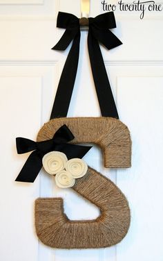 a door hanger made out of yarn and ribbon with the letter s on it