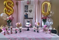 the table is decorated with balloons, cake and decorations for an 80th birthday party