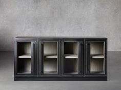 a black cabinet with three doors and shelves on one side, in front of a concrete wall