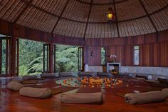 a living room filled with lots of pillows on top of a wooden floor next to windows