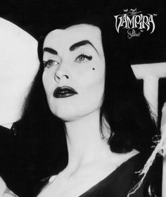 a black and white photo of a woman with long hair, wearing an evil make - up