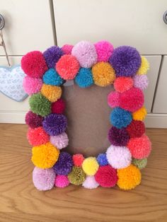 a multicolored pom - pom wreath on a table