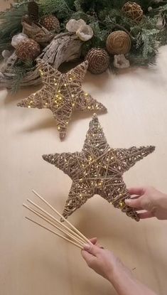 someone is decorating two star shaped christmas ornaments with sticks and lights on the table