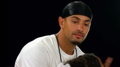 a man in white shirt and black headband sitting next to a person with dark hair