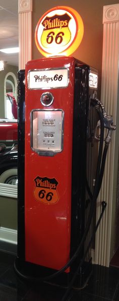 an old fashioned gas pump sitting on top of a black tile floor next to a sign that says phillips 66