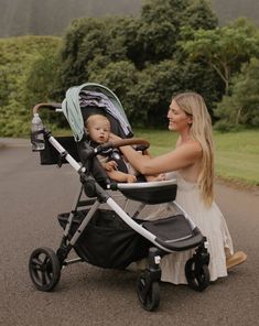 a woman is pushing a stroller with a baby in it on the side of the road