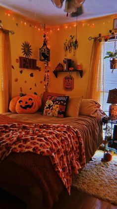 a bedroom decorated for halloween with pumpkins on the bed and decorations hanging from the ceiling