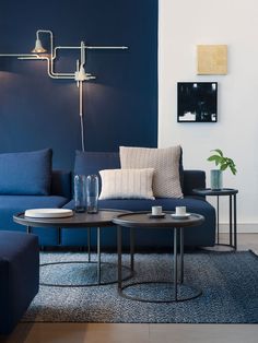 a living room with blue couches and two tables in front of the wall,