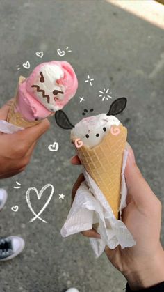 two people holding ice cream cones with pink and white frosting on them, while one person holds an ice cream cone in the other's hand