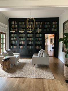 a living room filled with white furniture and lots of bookshelves full of books