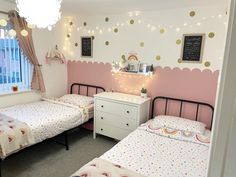 two twin beds in a room with pink walls and gold polka dots on the wall