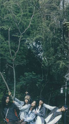 four young women sitting on the ground in front of trees