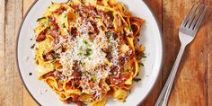 a white plate topped with pasta covered in sauce and parmesan cheese next to a fork