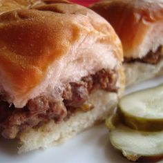 a close up view of a sandwich with meat and cheese on it next to a pickle