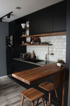 a kitchen with black cabinets and wooden stools