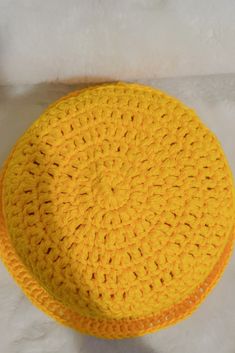 a yellow crocheted hat sitting on top of a white surface