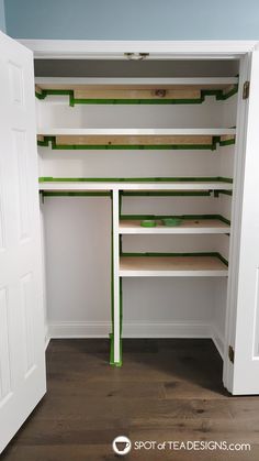 an empty closet with shelves and green tape on the bottom shelf, next to a white door