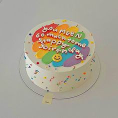 a birthday cake that is decorated with colorful confetti and happy faces on it