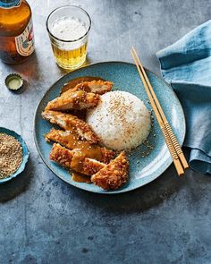 a plate topped with rice and chicken next to two beer glasses