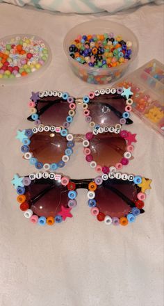 four pairs of sunglasses are sitting on a bed with candy and candies in the background