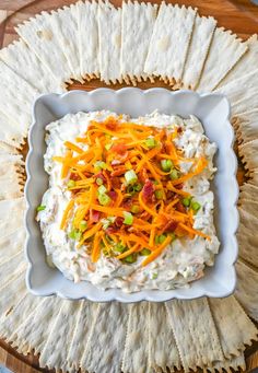 a white plate topped with mashed potatoes and carrots next to crackers on a wooden table