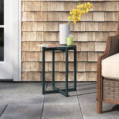 a chair and table on a patio with flowers in a vase next to the door