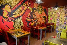 the interior of a restaurant with brightly colored walls and tables, chairs, and artwork on the wall