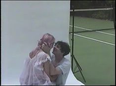 a man and woman standing next to each other on a tennis court holding racquets