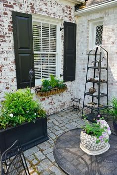 a brick house with black shutters and plants in the front yard, on instagram