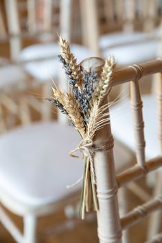 a bunch of dried flowers tied to a chair at an outdoor wedding ceremony with white chairs in the background