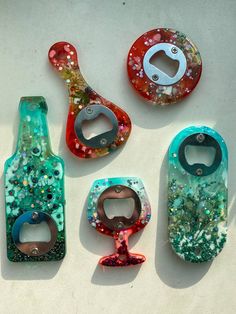 four bottle openers with different designs and colors on the top one has a corkscrew