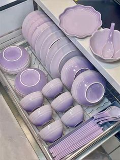 purple dishes and spoons are stacked in a dishwasher tray on the counter