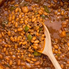 a wooden spoon in a pot filled with beans