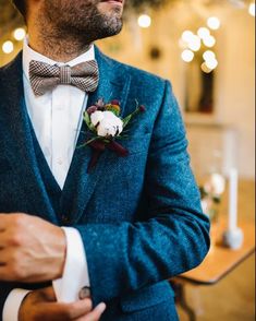 a man in a blue suit and bow tie is wearing a flower boutonniere